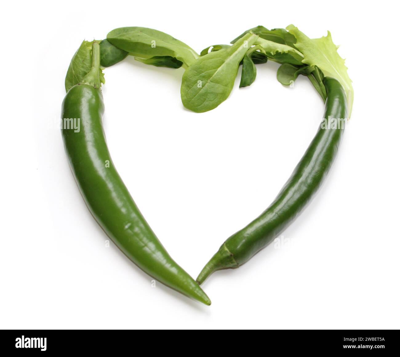 heart sign made from green chili pepper and lettuce leaves, salad leaf heart made of chillies, peppers, for decoration of menu cards, flyer, brochure Stock Photo