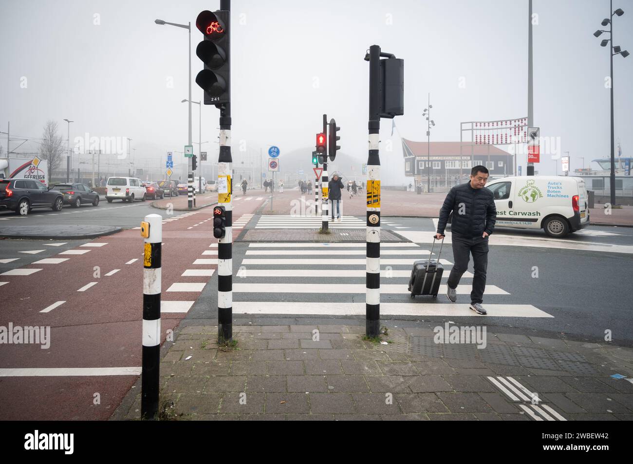 Man with suitcase crosses the road on a foggy morning in December Stock Photo
