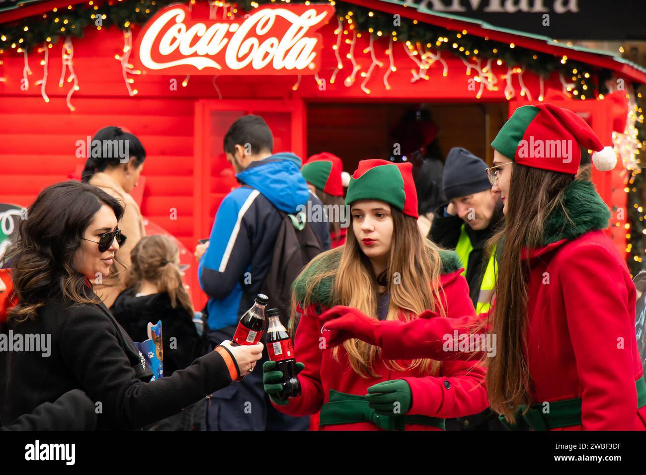 Belgrade, Serbia - January 5, 2024: Young Coca Cola promoters giving away free drinks to people during holiday promotion campaign on city street Chris Stock Photo
