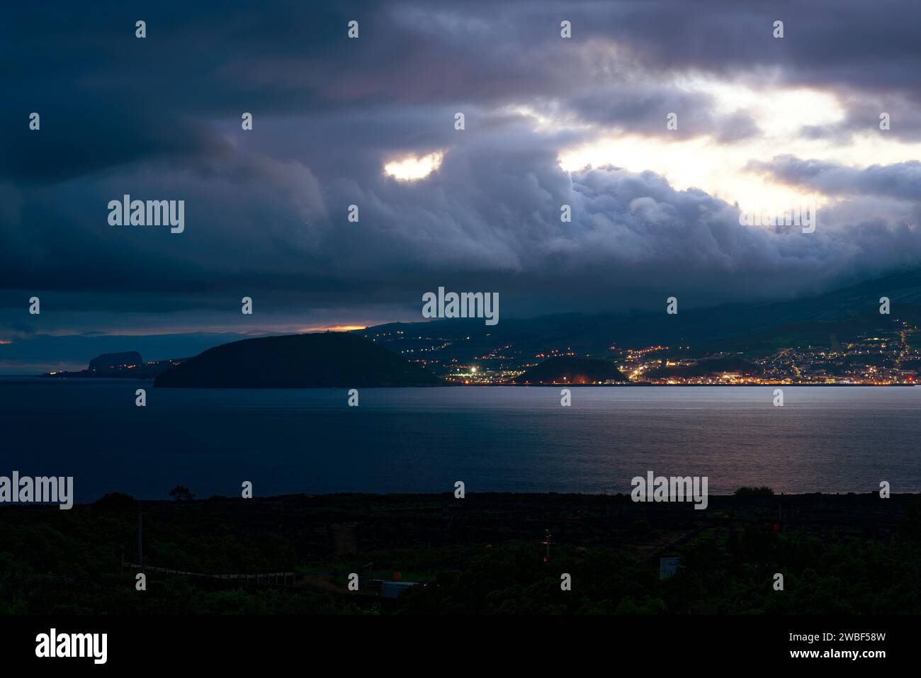 Night view of an illuminated coastal town of Horta under dramatic