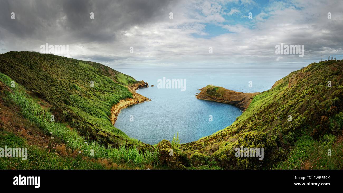 Panoramic view from Monte da Guia over a green coastline and bay on a cloudy day, Monte da Guia, Horta, Faial Island, Azores, Portugal Stock Photo