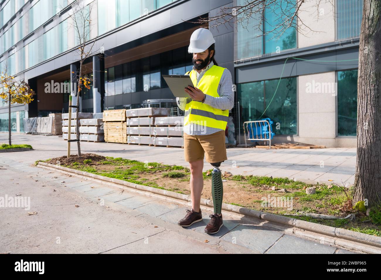 Engineer with prosthetic leg working on construction site wearing protective equipment Stock Photo