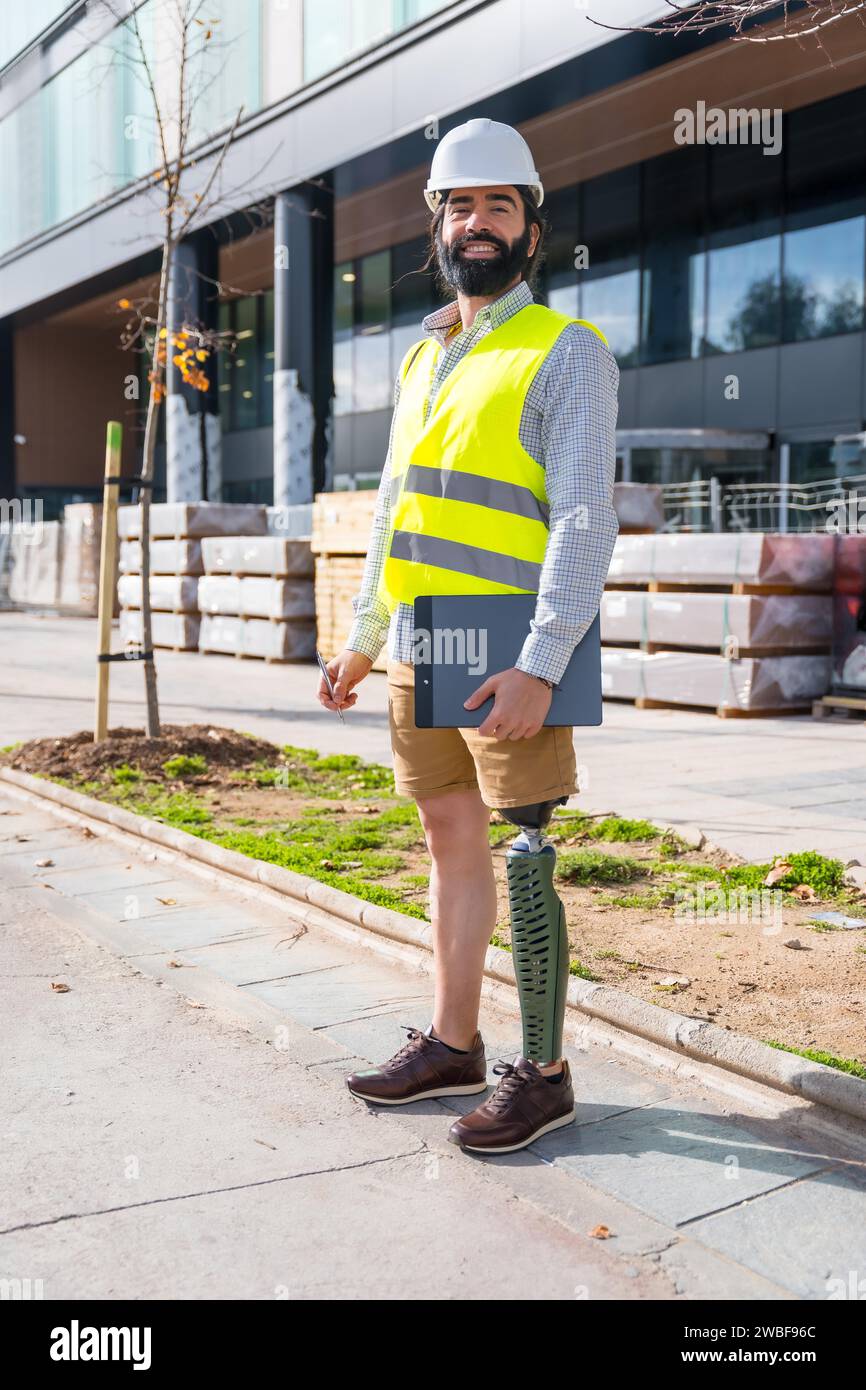 Vertical portrait of an employee with prosthetic leg working on construction site wearing protective equipment Stock Photo