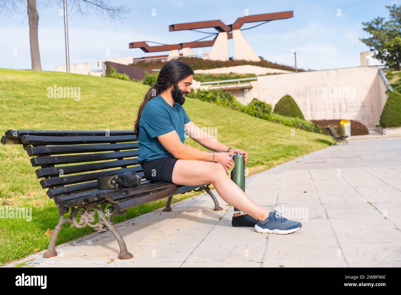 Active man adjusting his prosthetic leg before running outdoor in the park Stock Photo