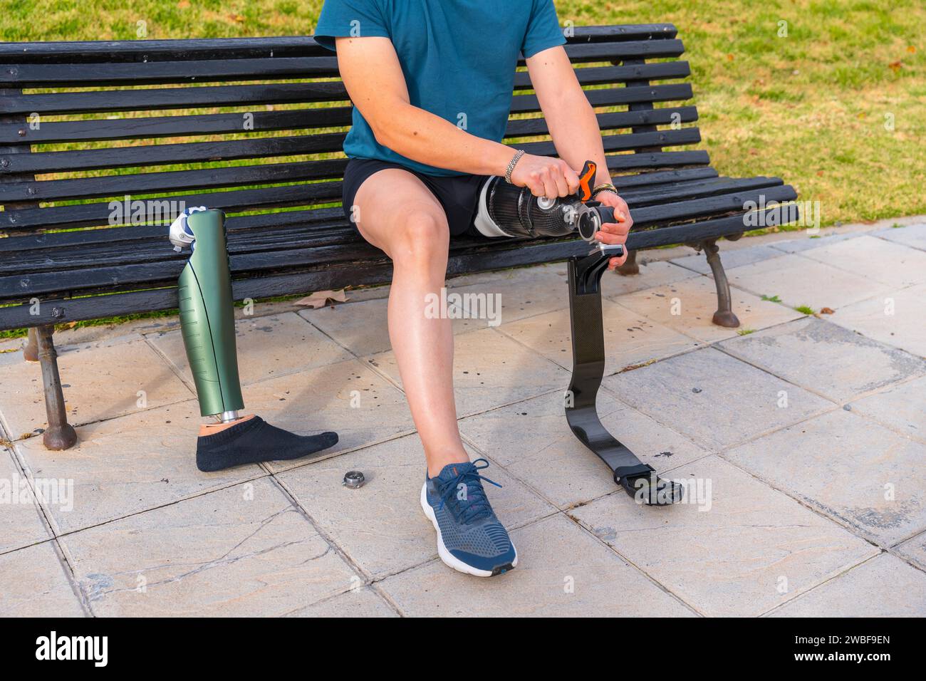 Sportsman adjusting the screws on an artificial prosthetic leg sitting on a bench before running Stock Photo