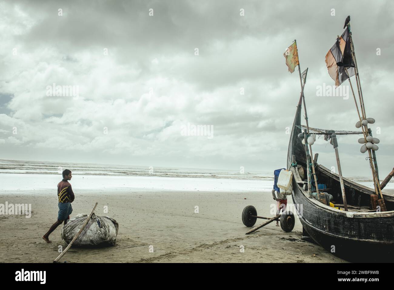 Fishing boat on the beach during a monsoon shower, Cox's Bazar, Bangladesh Stock Photo