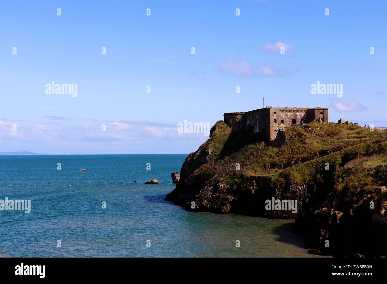 Historic stone castle situated on a scenic island surrounded by blue seas in Tenby. Stock Photo