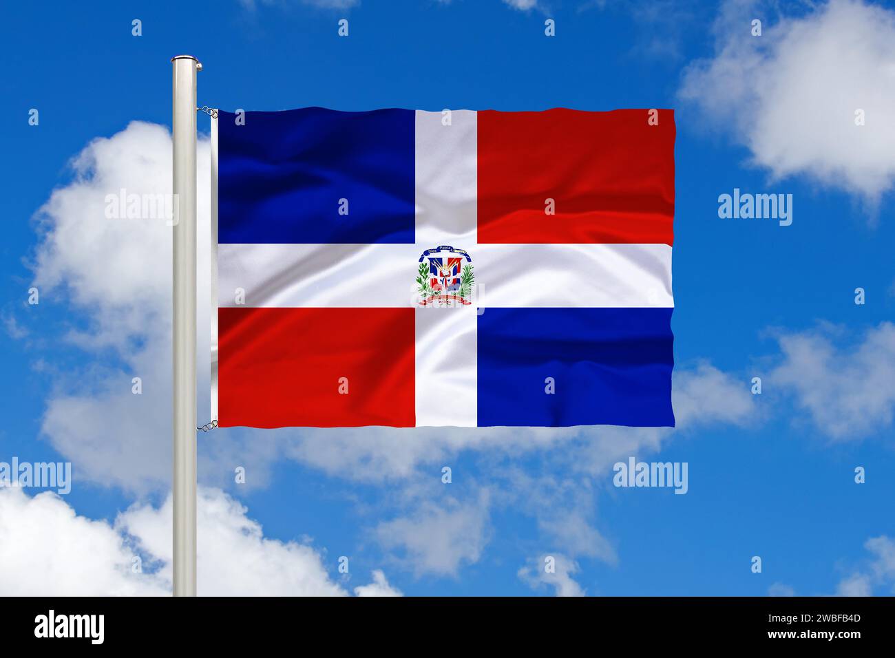 National flag of the Dominican Republic, island of Hispaniola, in front of cumulus clouds and blue sky, studio Stock Photo