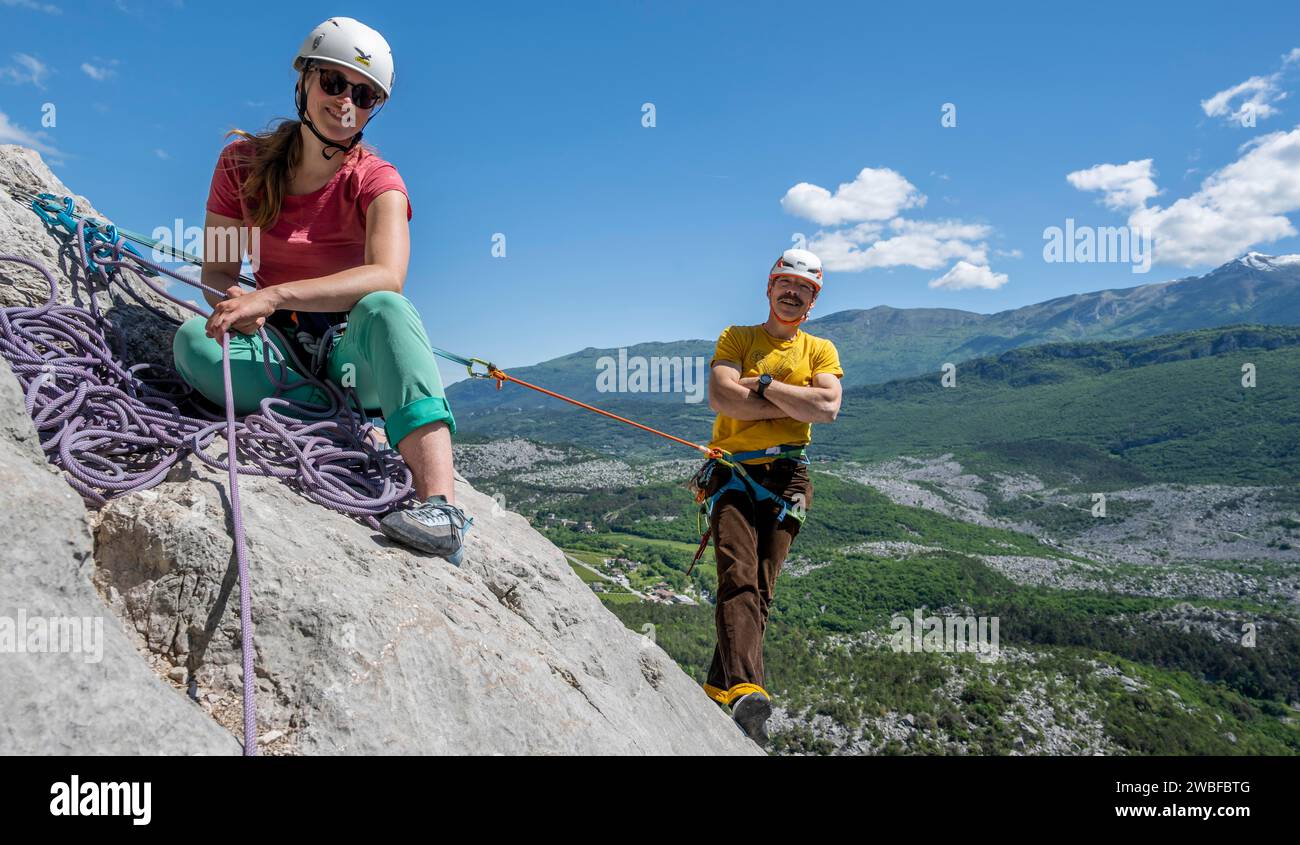 Two climbers belaying each other while climbing a rock face, alpine climbing with rope, Arco, Italy, AI generated Stock Photo