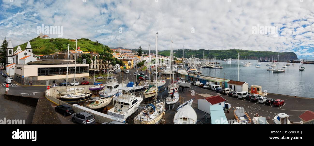 Wide angle shot of the harbour of Horta with boats, buildings and cars on the coastal road, Horta, Faial Island, Azores, Portugal Stock Photo