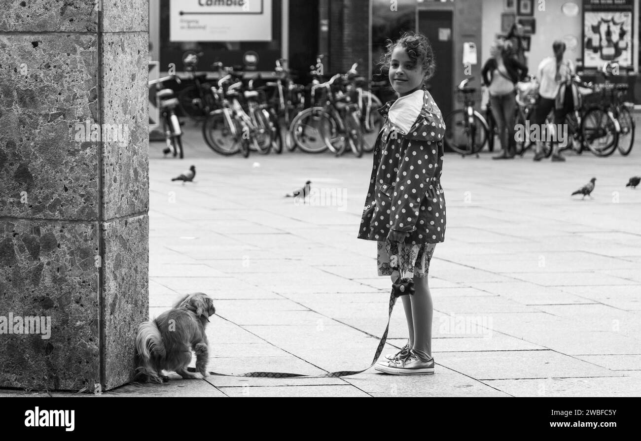 A little girl holds the leash of a dog on a city street, Hohenzollernbruecke, Cologne Deutz, North Rhine-Westphalia, Germany Stock Photo