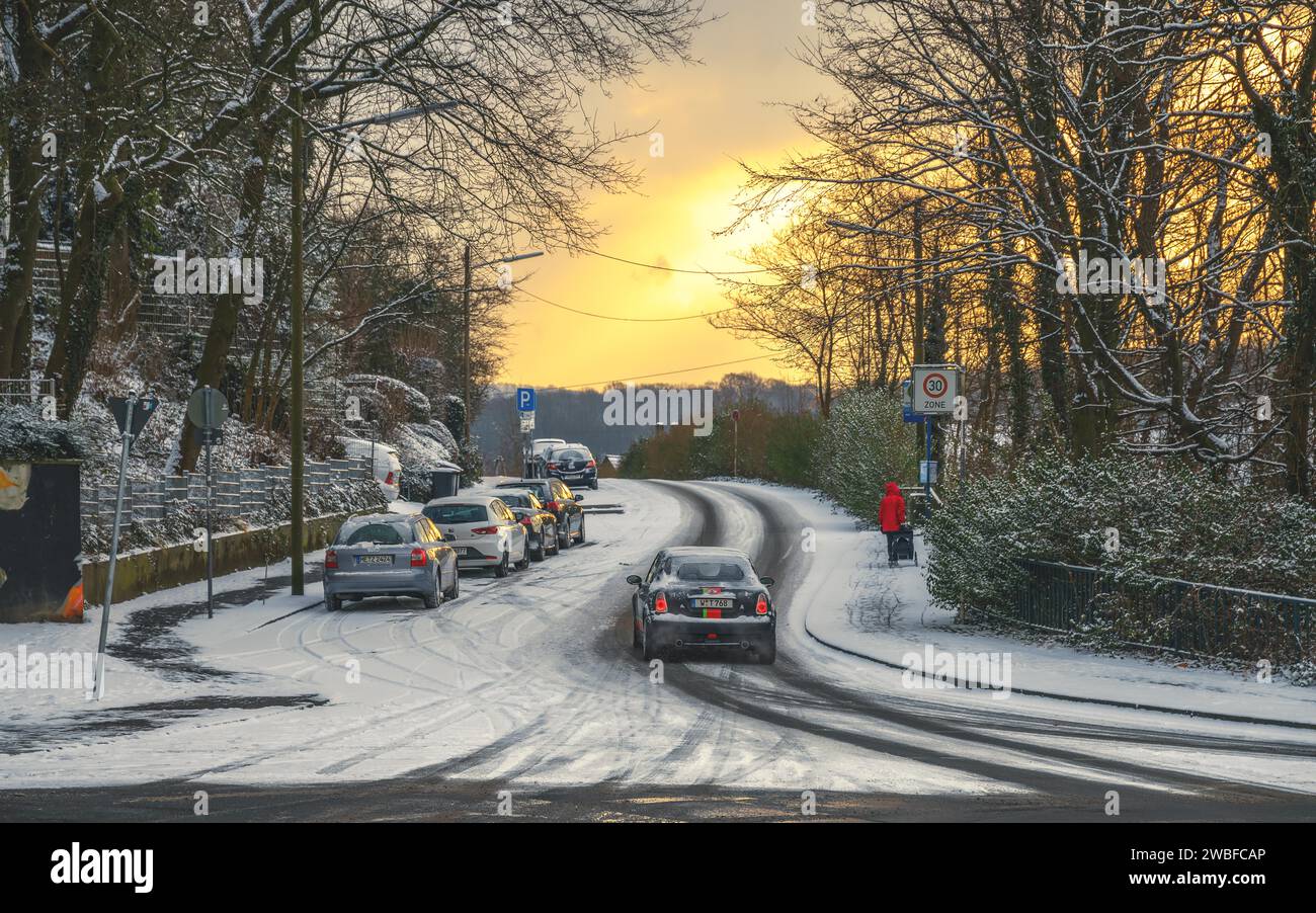 Cars driving carefully on a snow-covered road at dusk, Wuppertal Vohwinkel, North Rhine-Westphalia, Germany Stock Photo