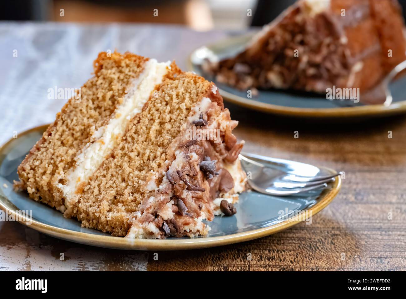 A serving or portion of cappuccino coffee cake plated and served on a cafe table. The cake is two tiered and has a buttercream filling and top Stock Photo