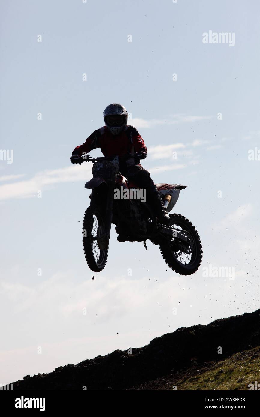 Thrilling rally bike race captures mid-air jump, showcasing adrenaline-fueled action. Stock Photo