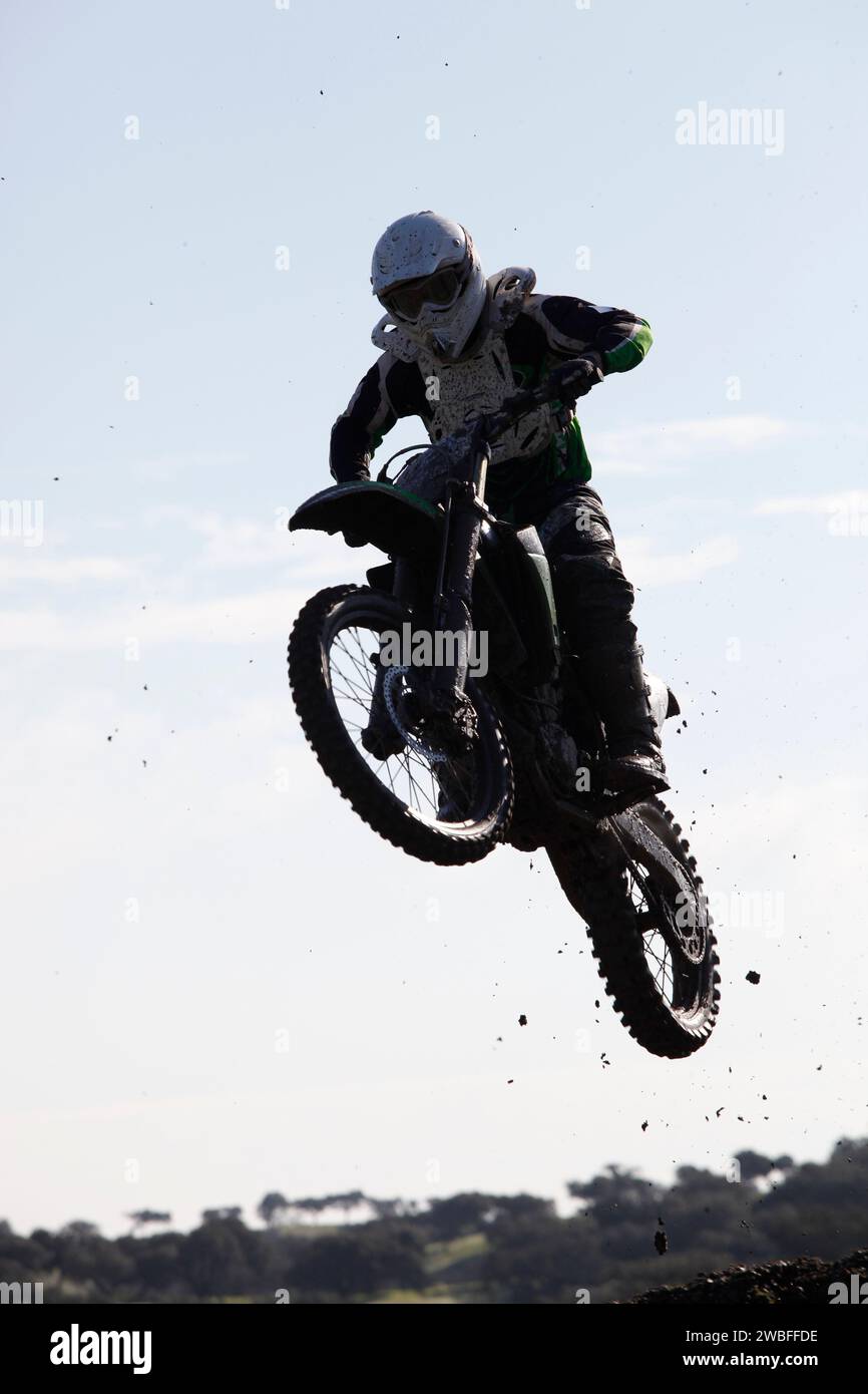 Thrilling rally bike race captures mid-air jump, showcasing adrenaline-fueled action. Stock Photo