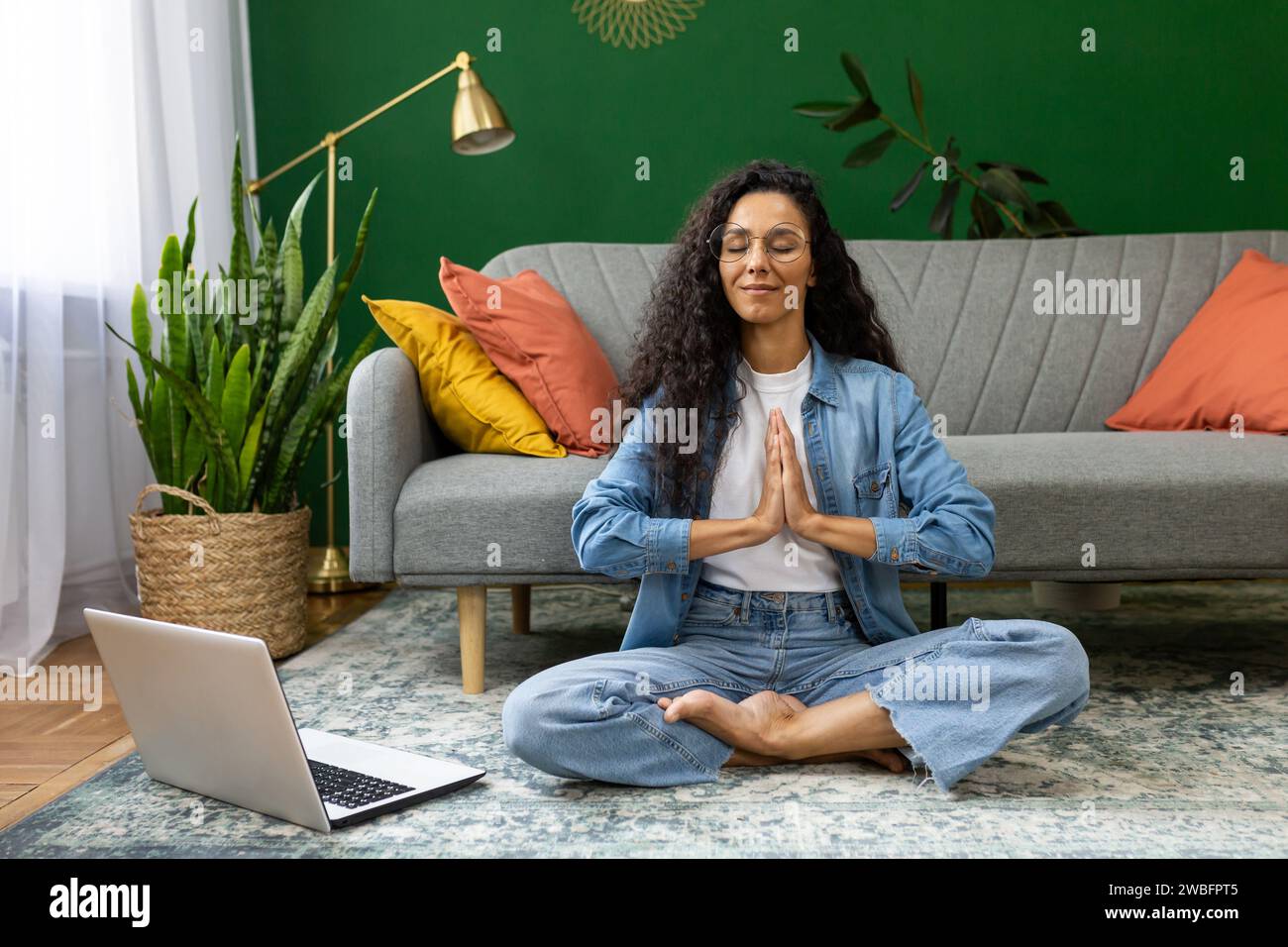 Young woman resting meditating in lotus pose sitting on floor at home ...