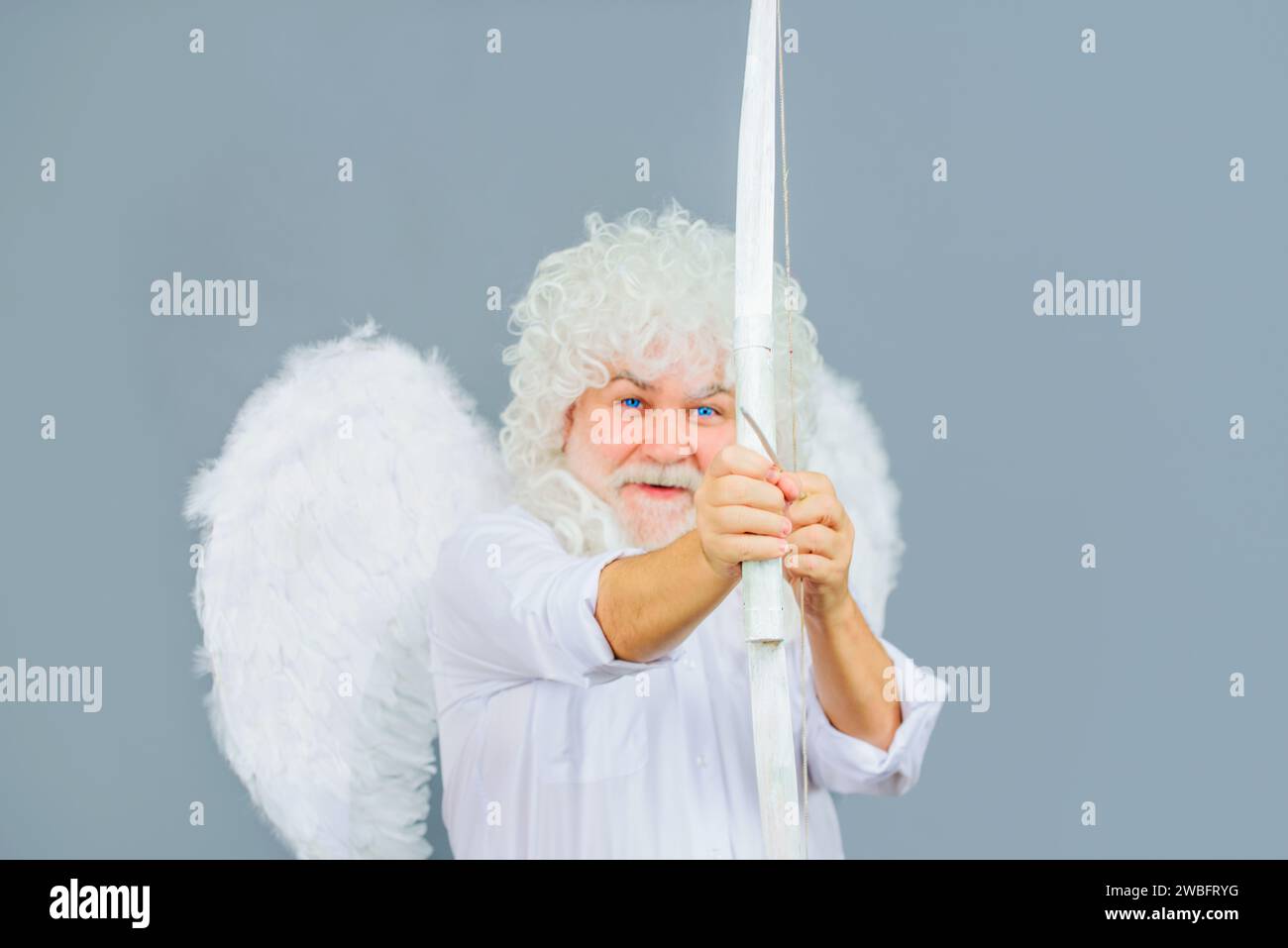 Happy Valentines Day. Cupid man in angel wings with bow and arrow. God of love. Valentines cupid angel shooting arrows of love. Smiling bearded man in Stock Photo