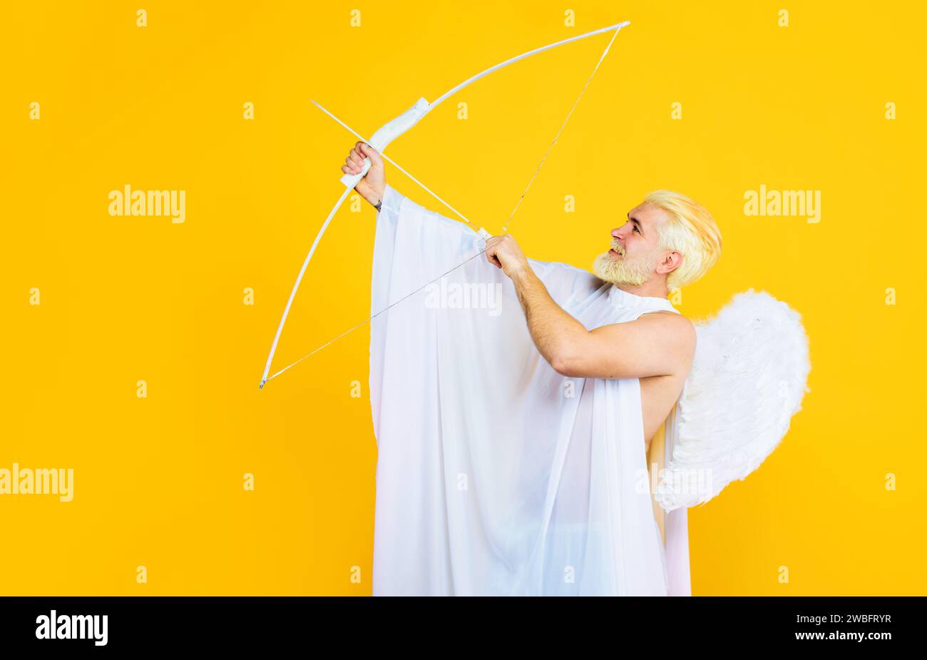 Valentines Day celebration. Cupid man in white angel wings with bow and arrow. God of love. Valentines day cupid angel shooting arrows of love Stock Photo