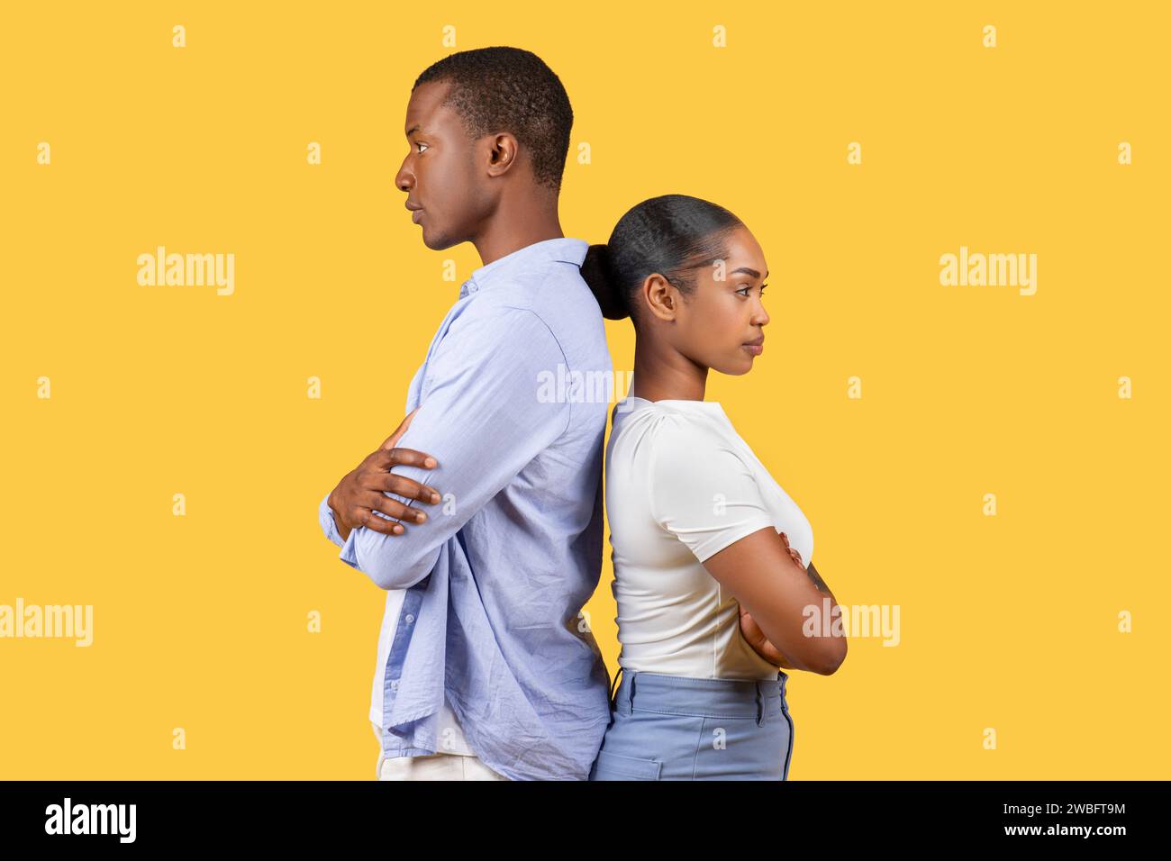Black couple standing backtoback, arms crossed, on yellow background