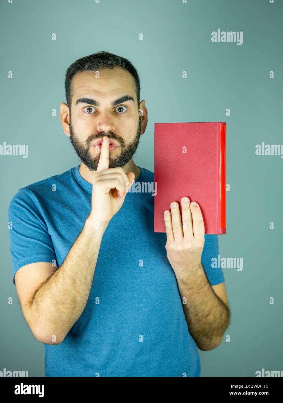 young bearded man asking for silence by gesturing with his index finger Stock Photo