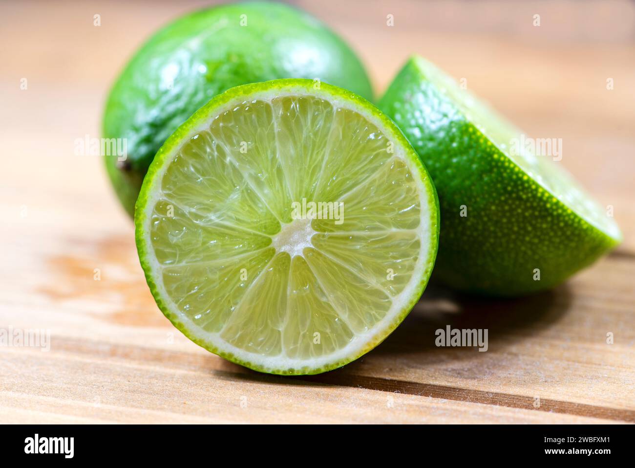 Group of three fresh fruity limes on a cutting board. Stock Photo