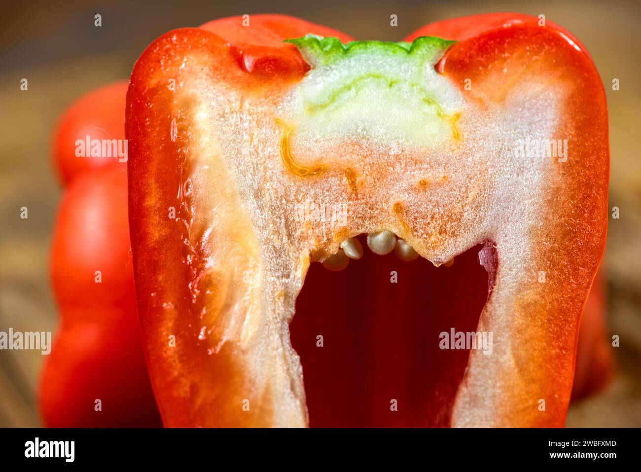 Natural and Fresh Whole Red Bell Peppers, one cut in half on a wooden board. Stock Photo