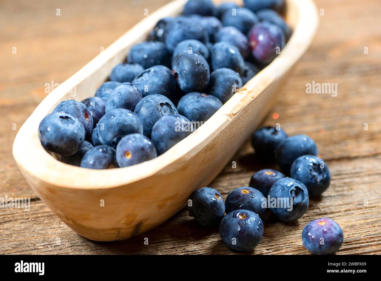 Wooden Bowl of fresh blueberries, in a small bowl on wooden plank,  nutritious food items. Stock Photo