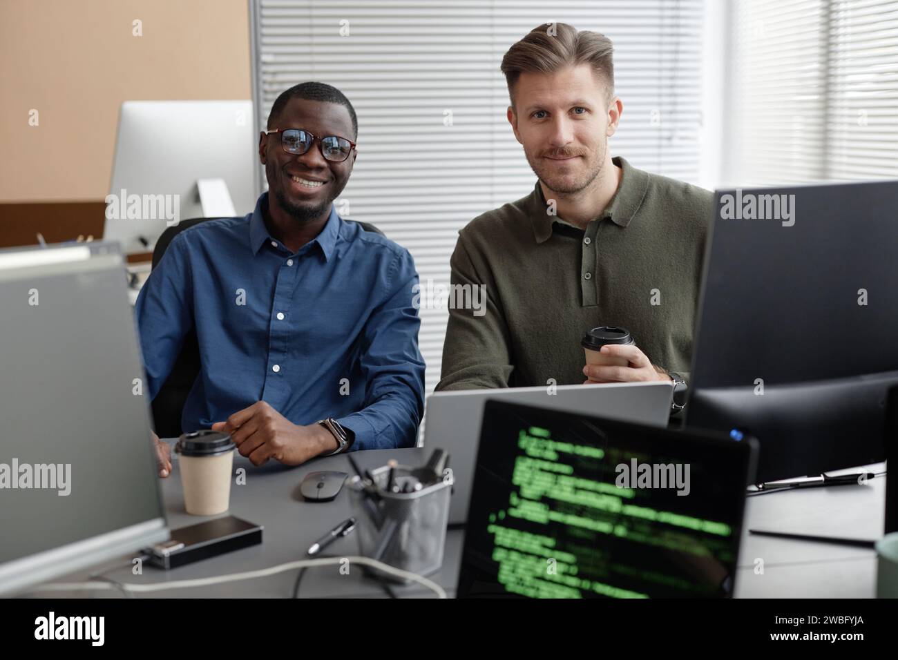 Two Diverse Programmers in Office Smiling at Camera Stock Photo