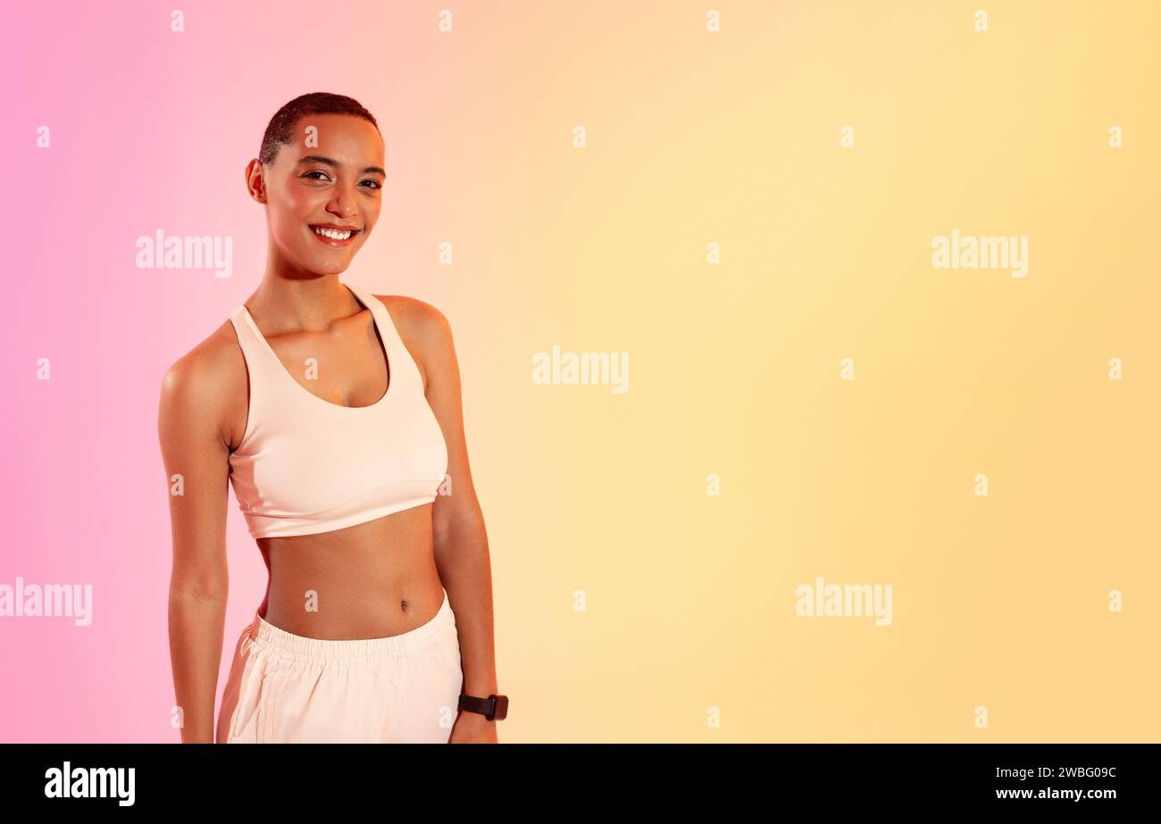 Radiant and fit young woman with a confident smile, wearing a white sports bra Stock Photo