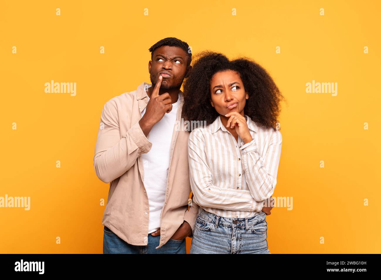 Thoughtful black couple with curious expressions on yellow Stock Photo