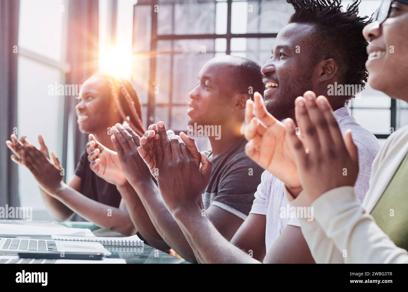 Multi ethnic business group greets somebody with clapping and smiling Stock Photo