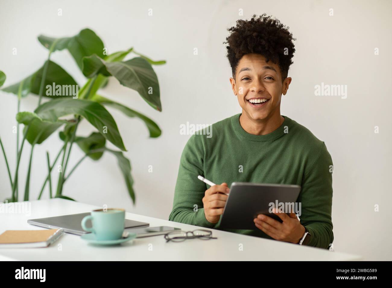 Happy african american guy designer working at cafe Stock Photo