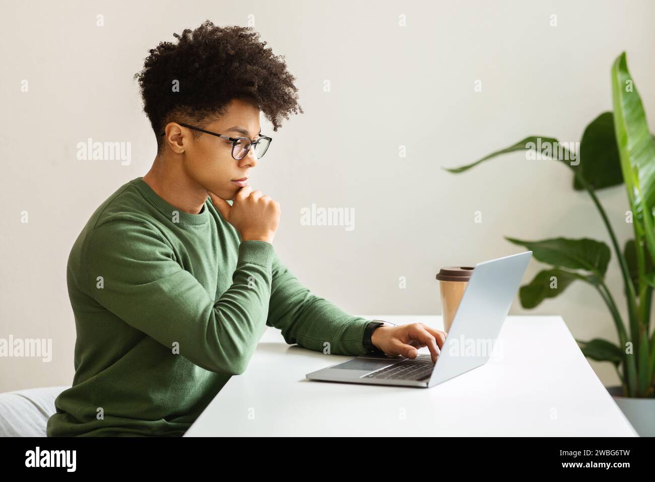 Concentrated young black guy freelancer working from cozy cafe Stock Photo