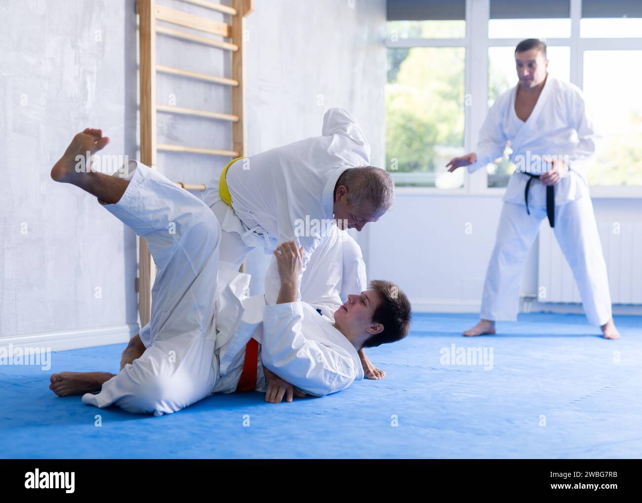 Aged man working on jiujitsu techniques in training fight with young