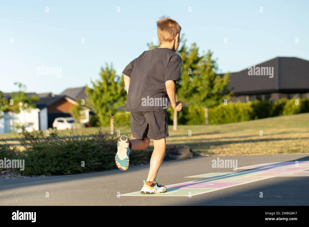 A boy is playing hopscotch on the asphalt in the playground. Active leisure for children.  Stock Photo