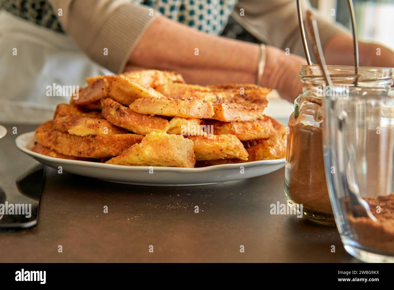 ingredients for the recipe of spanish toasts torrijas typical dish on the kitchen counter while the pastry chef is serving on the background. Stock Photo