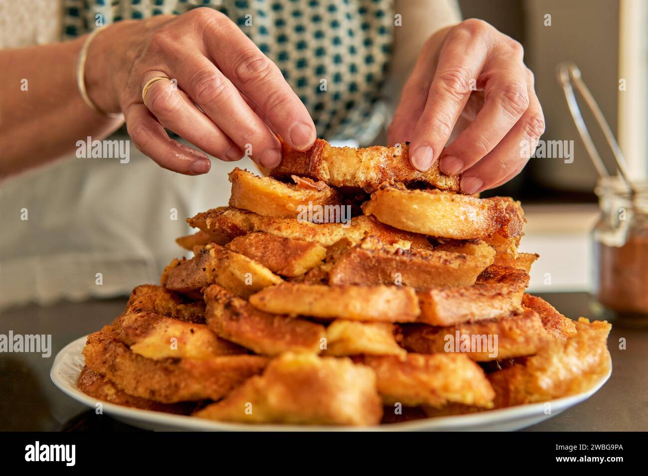 Close up of senior woman hands stacking easter dessert. Traditional spanish recipe of torrijas Stock Photo