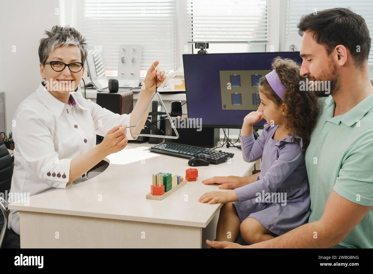 speech therapist working with child who has hearing problems. Rehabilitation teacher of the deaf consulting father with daughter speech therapist Stock Photo