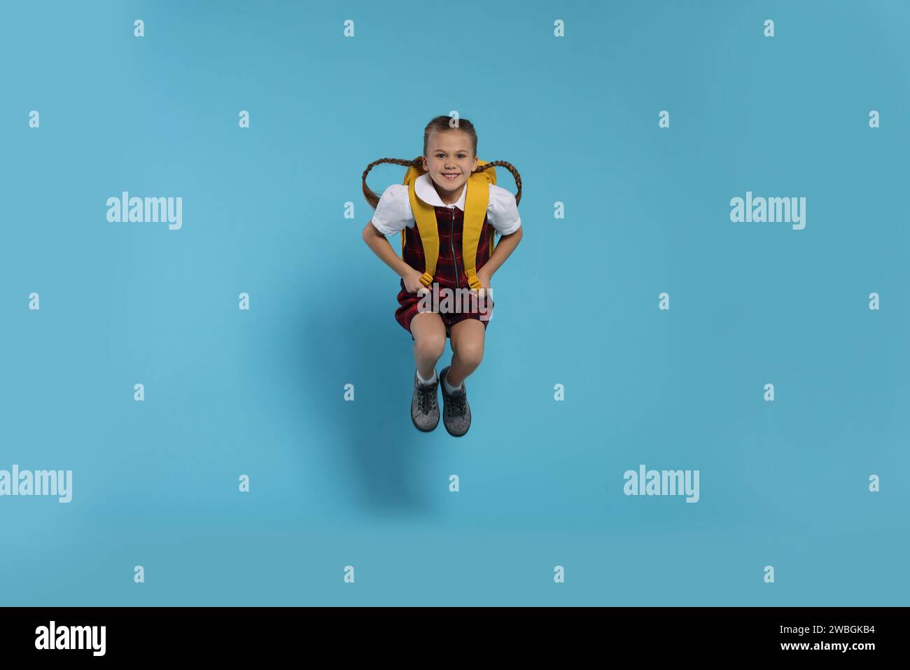 Happy schoolgirl with backpack jumping on light blue background Stock ...
