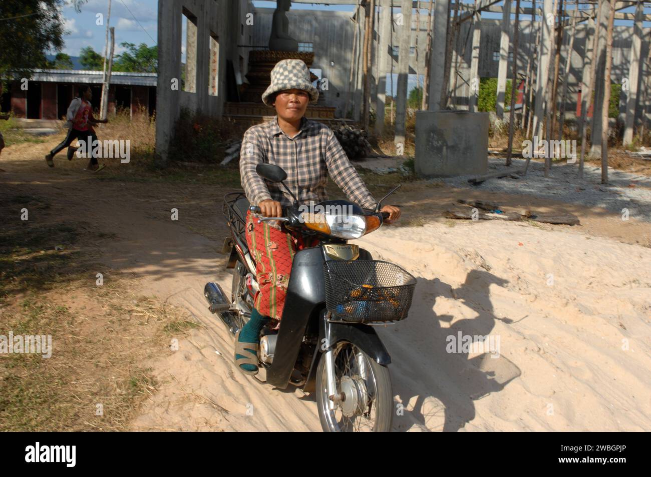 Old Lady riding a motorcycle, Beng Mealea, Cambodia. Stock Photo
