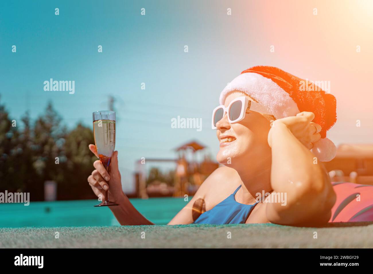Woman pool Santa hat. A happy woman in a blue bikini, a red and white ...