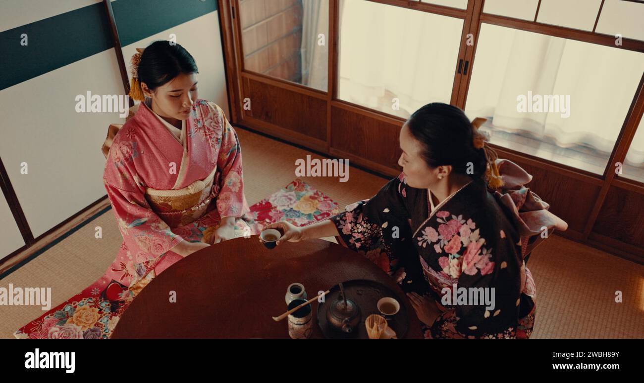 Women with traditional Japanese tea cup, kimono and relax with mindfulness, respect and conversation. Friends at calm tearoom with matcha drink, Asian Stock Photo