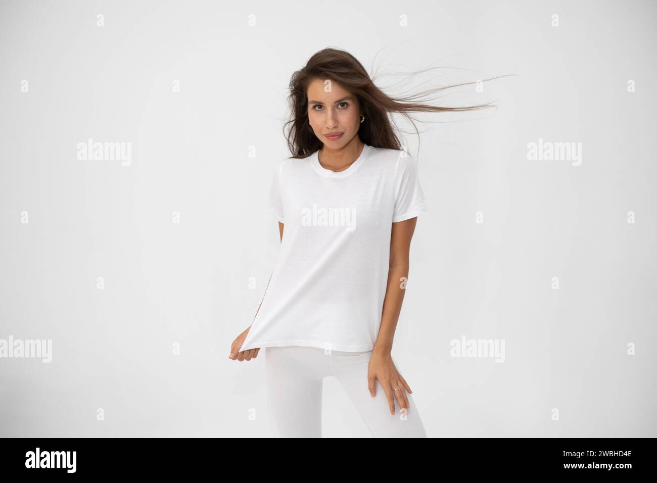 Beautiful brunette girl in a white T-shirt posing on white background ...