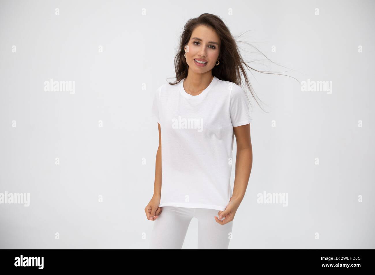 Beautiful brunette girl in a white T-shirt posing on white background ...