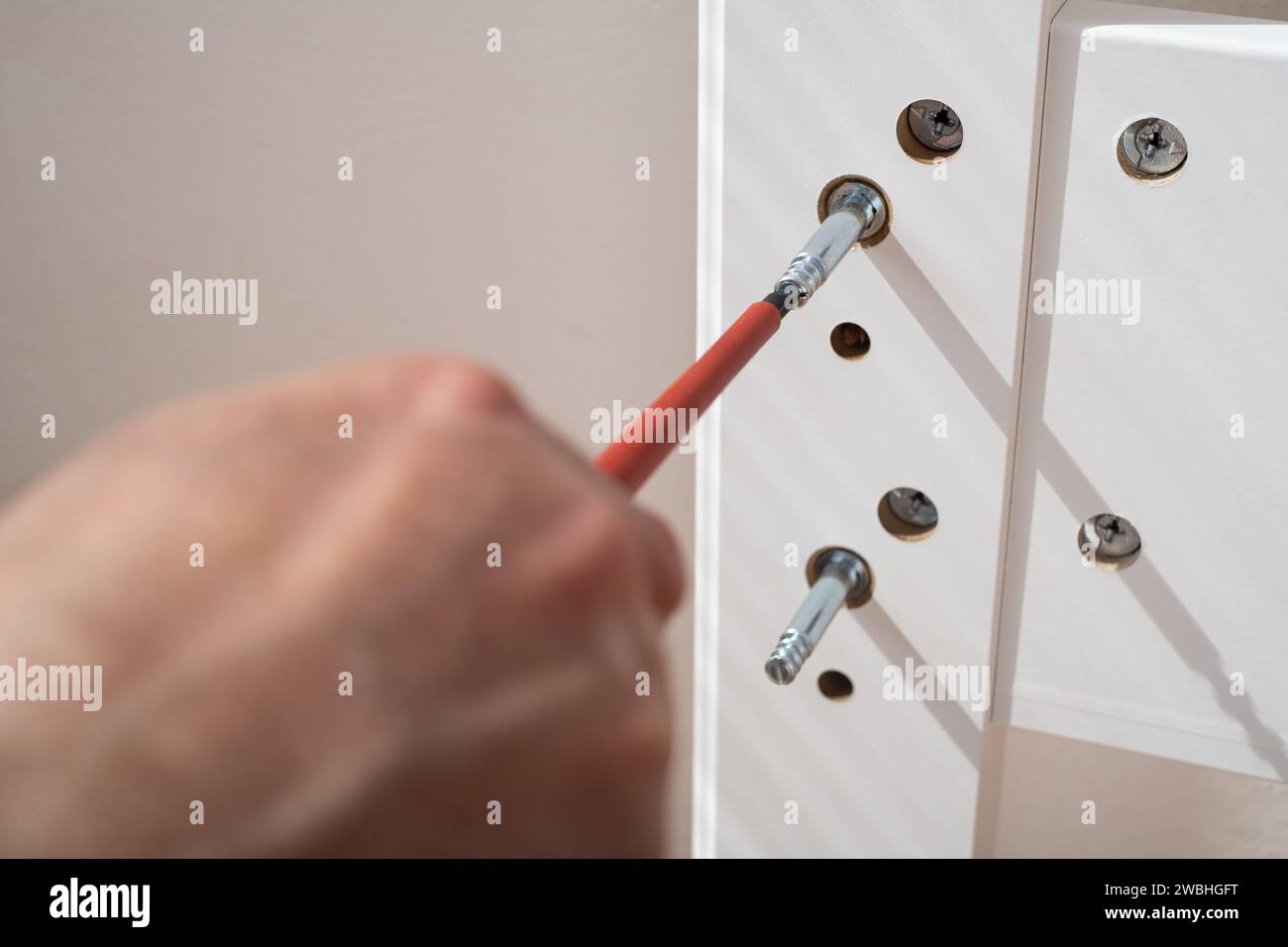The furniture assembler assembles the bed frame, twists the fixers