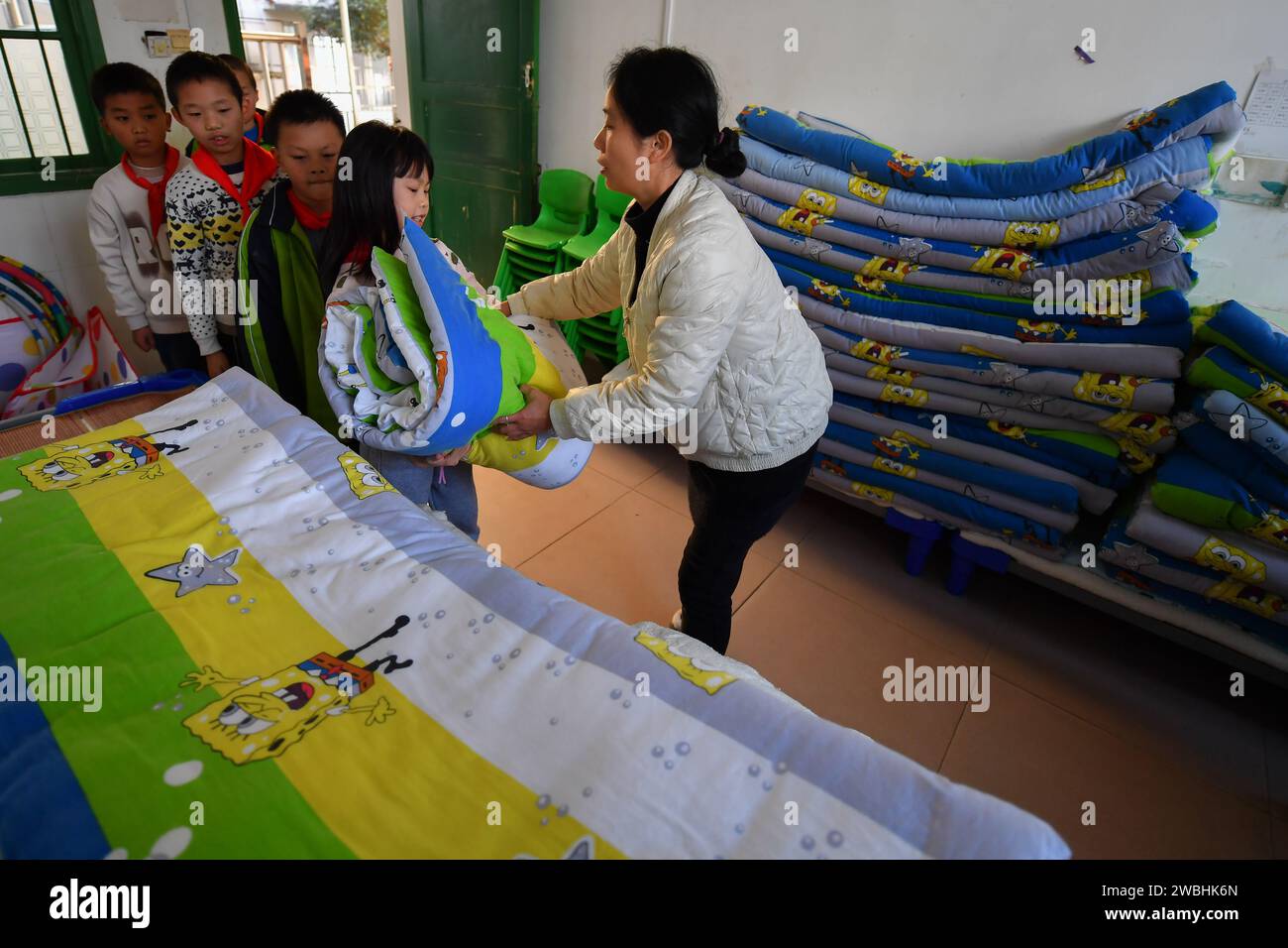 Changsha, China's Hunan Province. 10th Jan, 2024. A teacher hands out quilts before nap time at a primary school in Liuyang City, central China's Hunan Province, Jan. 10, 2024. A batch of foldable chairs have been put into use at the classrooms of a primary school in Longfu Town of Liuyang City. The chairs, which can be laid down when students need to take a nap at noon, can greatly improve the sleeping quality of students. Credit: Chen Zeguo/Xinhua/Alamy Live News Stock Photo
