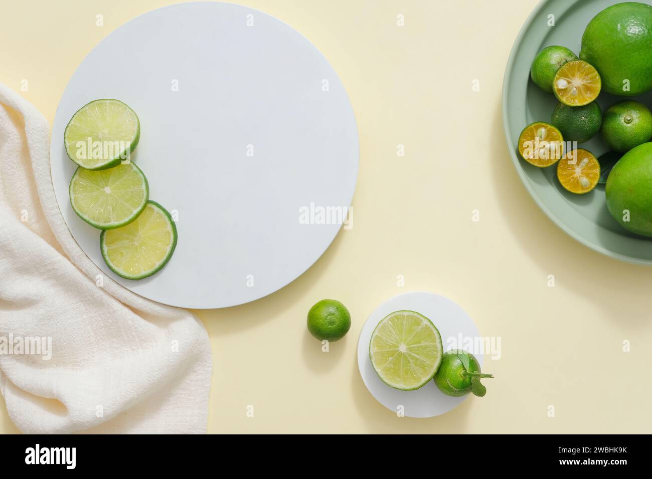 Light background featured podiums in round-shaped, white towel and a dish of kumquat and lime. Vacant space for beauty product advertising of Lime and Stock Photo