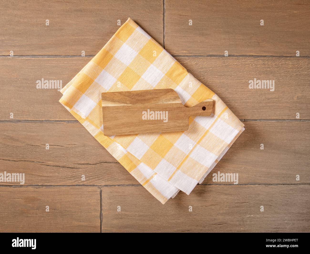 Rustic Kitchen Background with Cutting Board and Yellow Checkered Napkin on Wooden Table Stock Photo