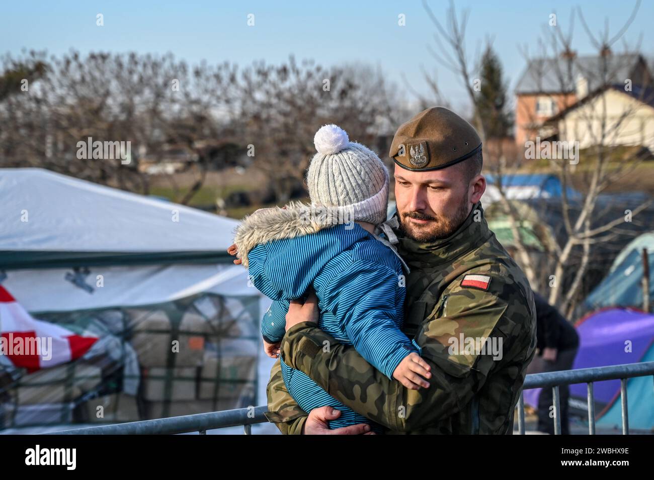 Polish soldier carries a refugee baby. Refugees from Ukraine escaping from war. Ukrainian refugees on crossing the border to Poland. Stock Photo