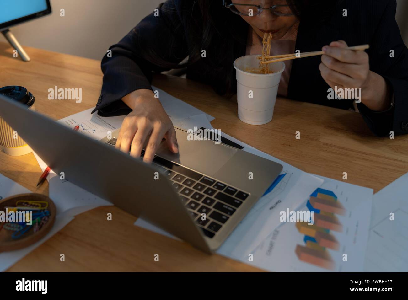 Asian businesswoman eating at computer hires stock photography and